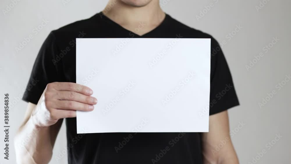 The man shows a blank sheet of paper. On a gray background. The man shows a blank sheet of paper. On a gray background.