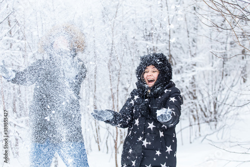 Love  relationship  season and friendship concept - man and woman having fun and playing with snow in winter forest