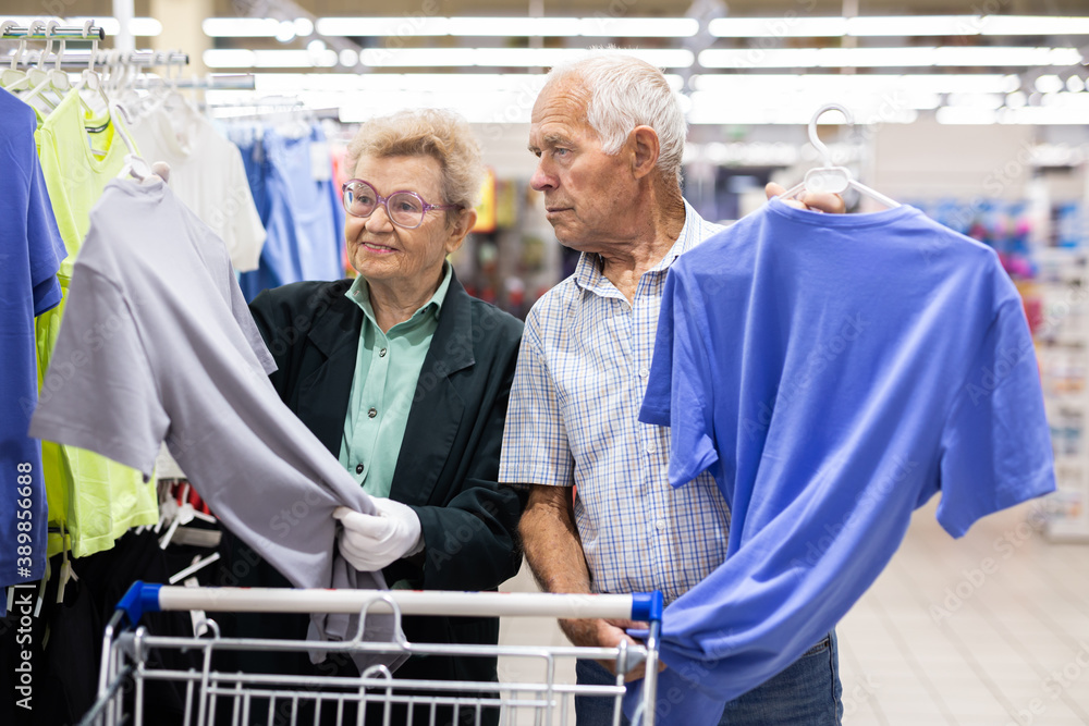 mature european couple chooses tee shirt in clothing department of supermarket
