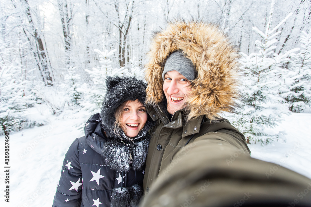 Season and relationship concept - Funny couple taking selfie in the winter time