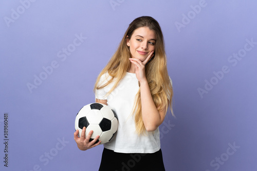 Young blonde football player woman isolated on purple background looking up while smiling © luismolinero