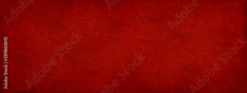 Abstract red background. Toned rough grainy texture. Decorative plaster on a concrete wall. Wide banner. Bright festive background for your design.