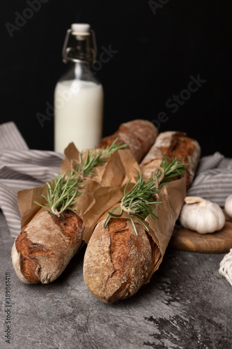 Two wheat baguettes and a bottle of milk on the table.