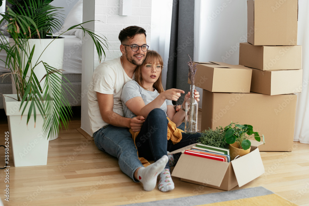 Boyfriend and girlfriend are moving into the apartment. Happy couple is unpacking their belongings. Boyfriend and girlfriend are moving into the apartment. Happy couple is unpacking their belongings.