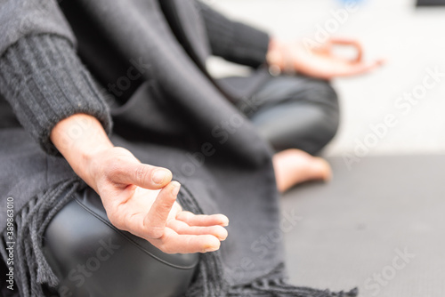Yoga teachers protesting against the blockade and restrictions of Covid-19 in a square in Brescia, Italy. Shot of the hands resting on the knees of the crossed legs. People are meditating.