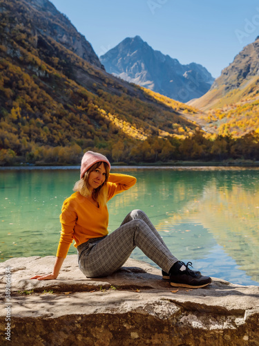 Attractive woman at crystal lake in the autumnal mountains. Mountain lake and hiker