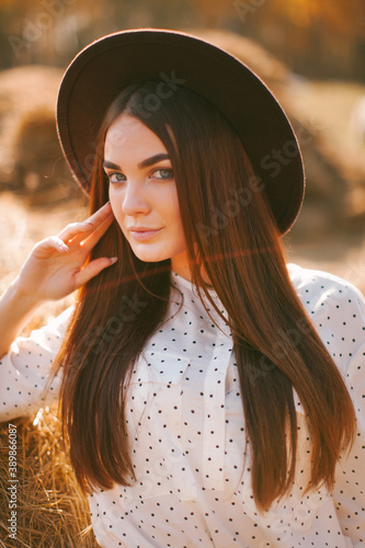 Young girl in dress and hat posing on the farm on a sunny day.