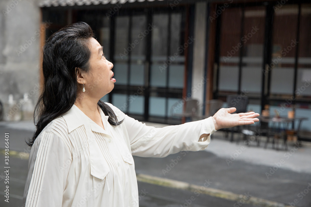 unhappy middle aged asian woman office worker worrying about the rain shower while traveling unhappy middle aged asian woman office worker worrying about the rain shower while traveling