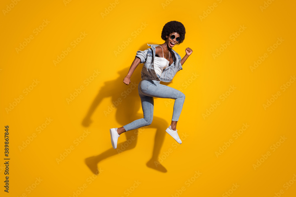 Full length photo of sportive young lady wear casual denim outfit jumping running isolated yellow color background