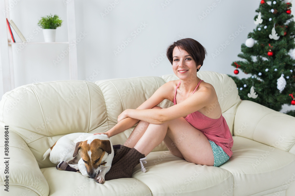 Happy young woman with lovely dog in living room with christmas tree. Holidays concept. Happy young woman with lovely dog in living room with christmas tree. Holidays concept.