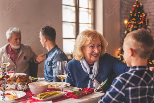 Grandmother giving present to grandson during family Christmas dinner