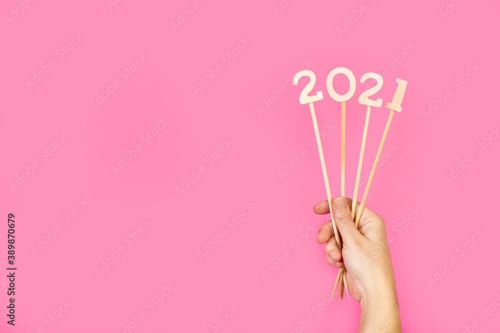 Año 2021. Mano de mujer sosteniendo números de madera sobre un fondo rosa liso y aislado. Vista de frente. Copy space. Concepto: Año Nuevo