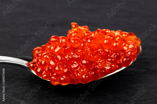 Red caviar in a spoon on a slate background.