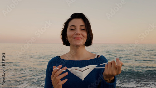 Giovane ragazza con maglia blu e mascherina passeggia in riva al mare photo
