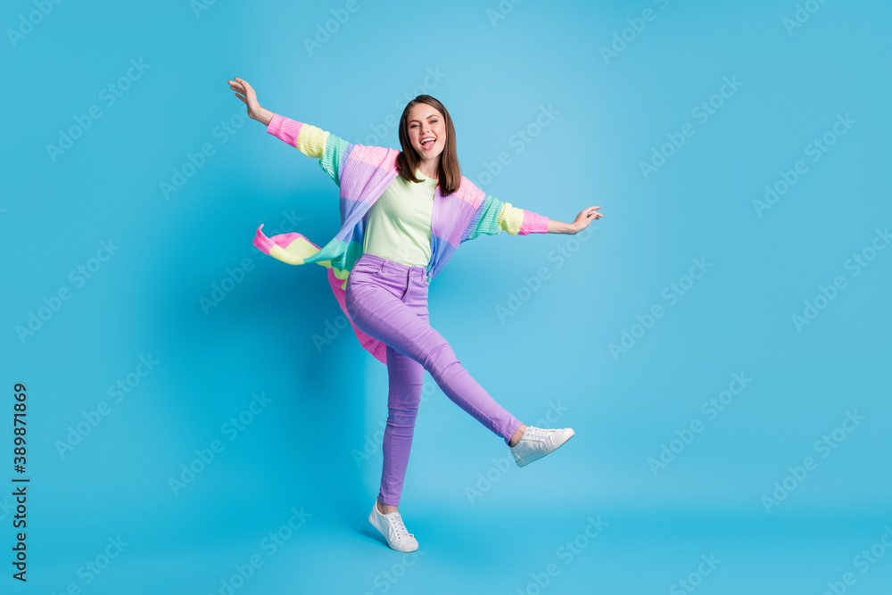 Obraz premium Full length photo of sweet funny lady wear casual colorful outfit dancing arms hands sides standing one leg isolated blue color background