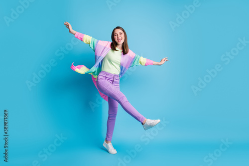 Full length photo of sweet funny lady wear casual colorful outfit dancing arms hands sides standing one leg isolated blue color background