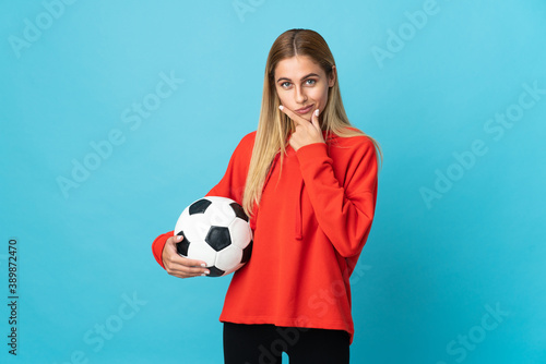 Young football player woman isolated on blue background thinking