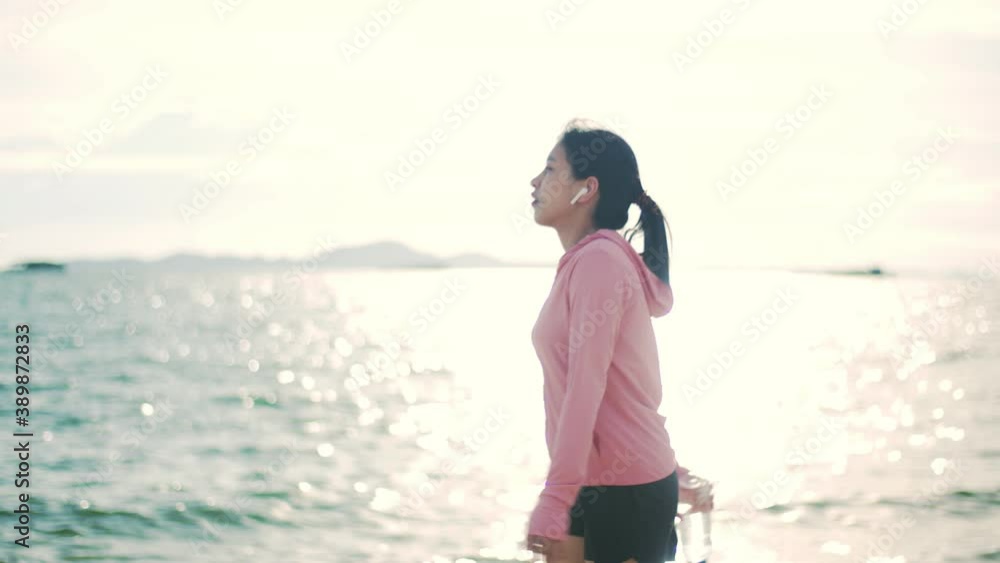 Sportsperson walking on the beach in the sunrise morning. Woman in sportswear runner taking a break after running activity. Healthy lifestyle concept. Sportsperson walking on the beach in the sunrise morning. Woman in sportswear runner taking a break after running activity. Healthy lifestyle concept.