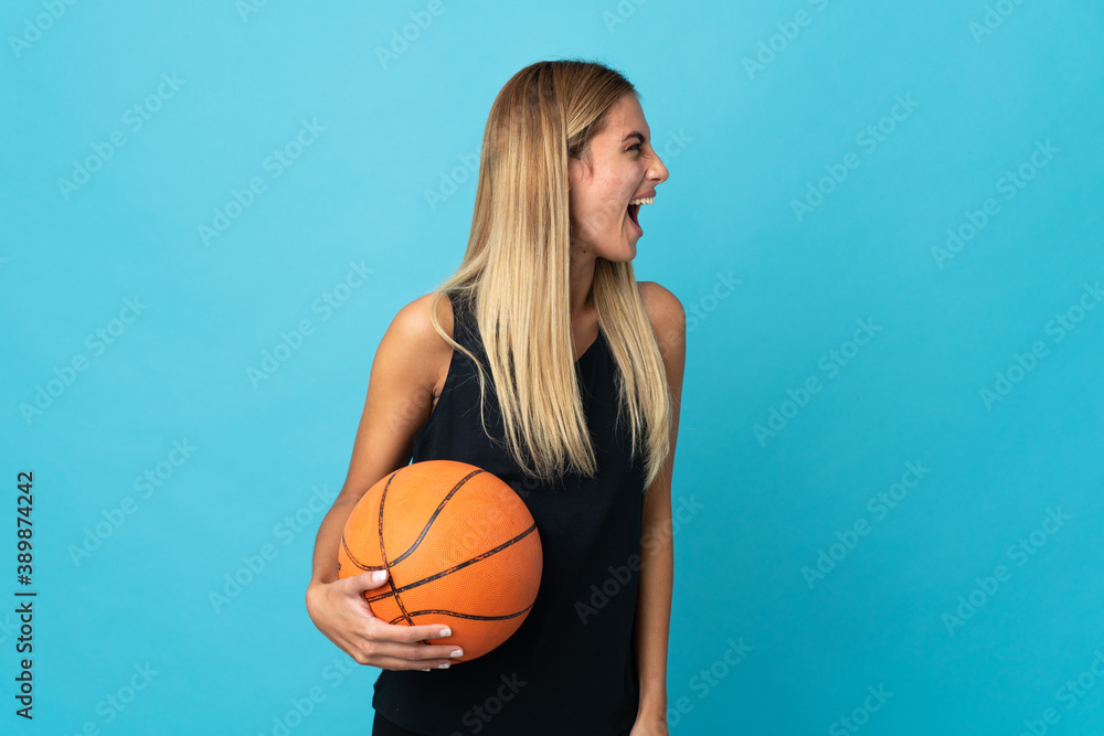 Young woman playing basketball  isolated on white background laughing in lateral position