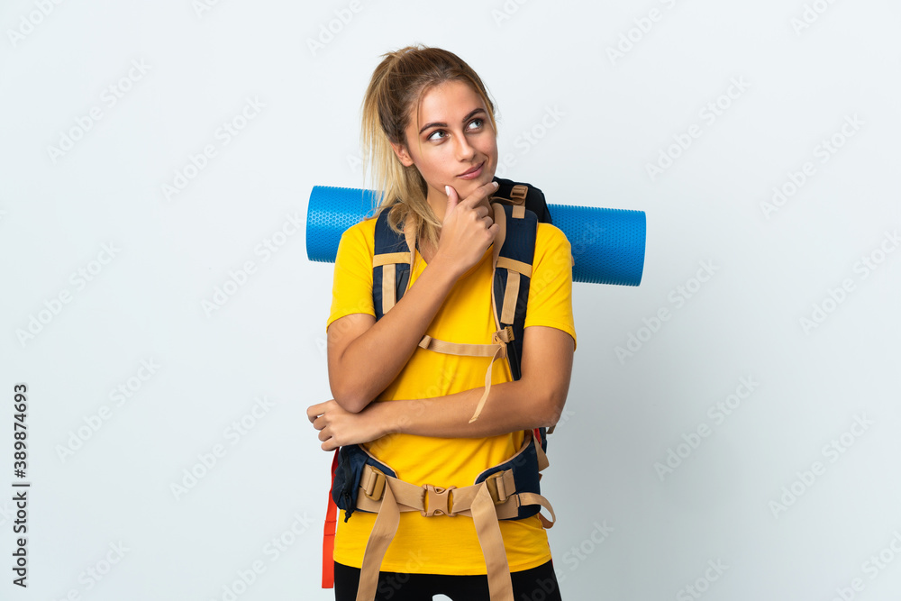 Young mountaineer woman with a big backpack isolated on white background having doubts and thinking Young mountaineer woman with a big backpack isolated on white background having doubts and thinking