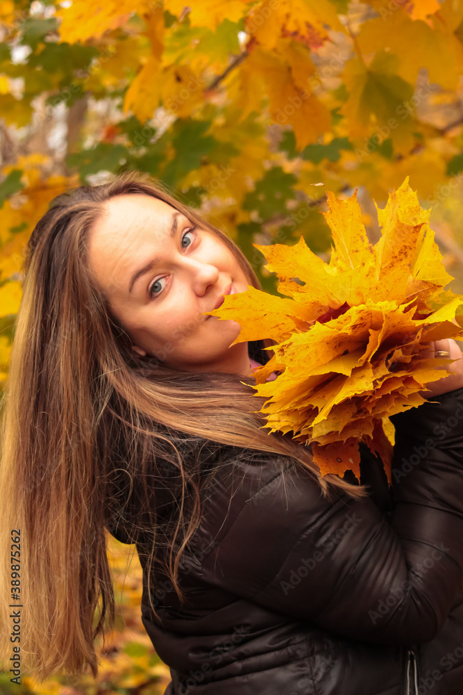 Autumn portrait of a young woman with yellow maple leaves in the forest. Autumn atmosphere in the forest with a picture of a young woman Autumn portrait of a young woman with yellow maple leaves in the forest. Autumn atmosphere in the forest with a picture of a young woman