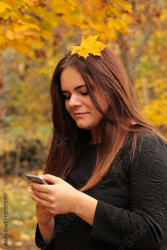 Young woman using phone. People in the autumn forest uses the phone.