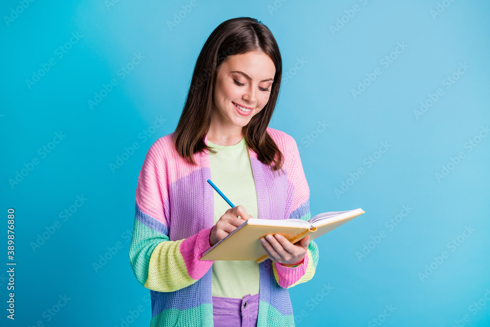 Photo of pretty young woman write look copybook creative project isolated on shine blue color background Photo of pretty young woman write look copybook creative project isolated on shine blue color background
