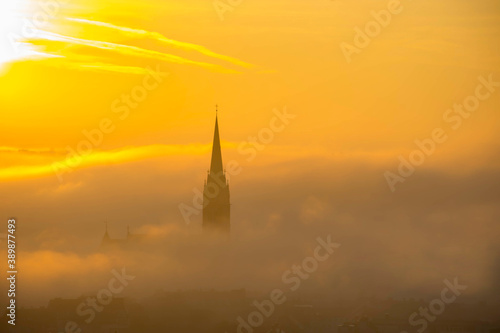 Church of the Sacred Heart of Jesus surrounded by fog and clouds, in Graz, Styria region, Austria, at sunrise. Beautiful foggy morning over the city of Graz, in autumn