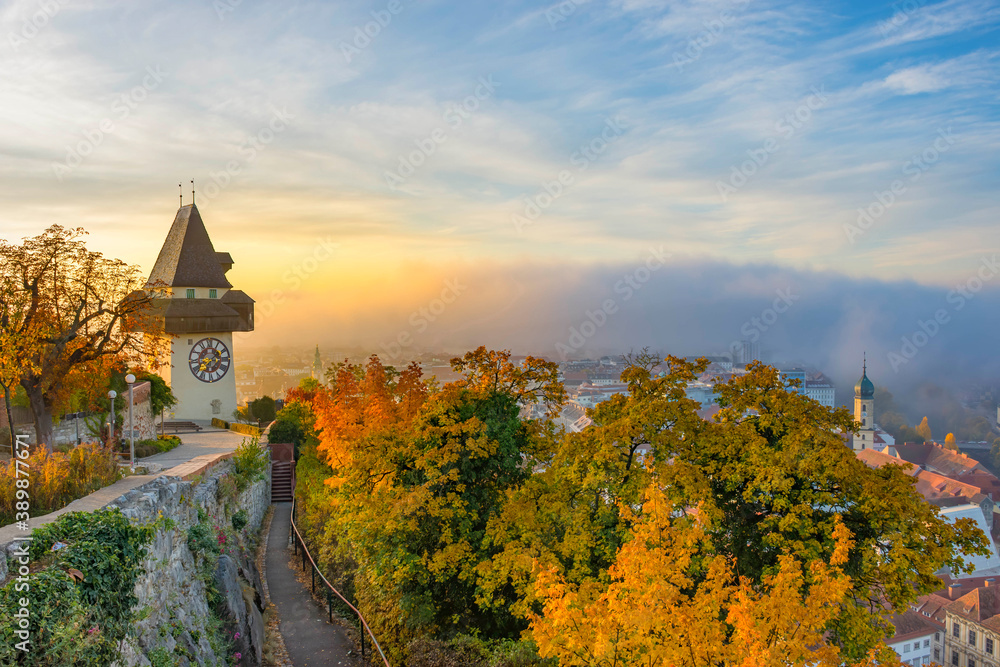 The famous clock tower on Schlossberg hill, in Graz, Styria region, Austria, at sunrise. Beautiful foggy morning over the city of Graz, in autumn