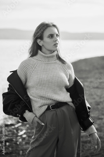 Young beautiful girl walking. Summer landscape, good weather. Sand beach, sea. Windy day. Warm clothes. Nature and freedom. Long hair, big eyes and lips. 