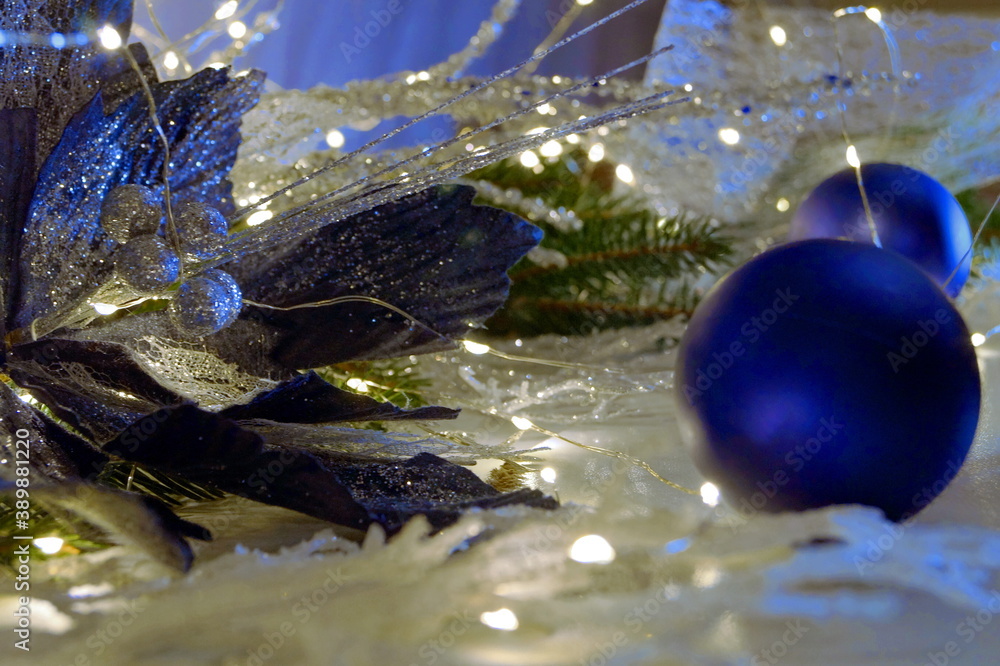 Dark blue New Year's ball in the bright lights of the New Year's garland with branches of a Christmas tree. New Year. Christmas Dark blue New Year's ball in the bright lights of the New Year's garland with branches of a Christmas tree. New Year. Christmas