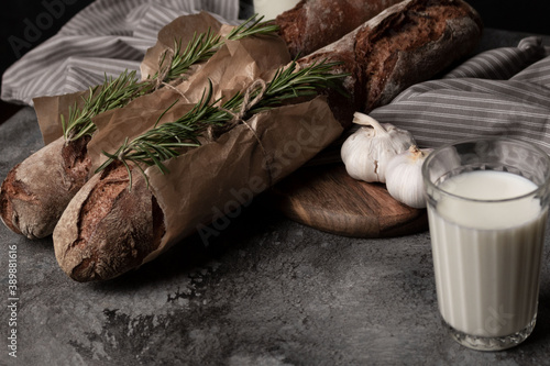 Wheat bread, garlic and a glass of milk on the table.