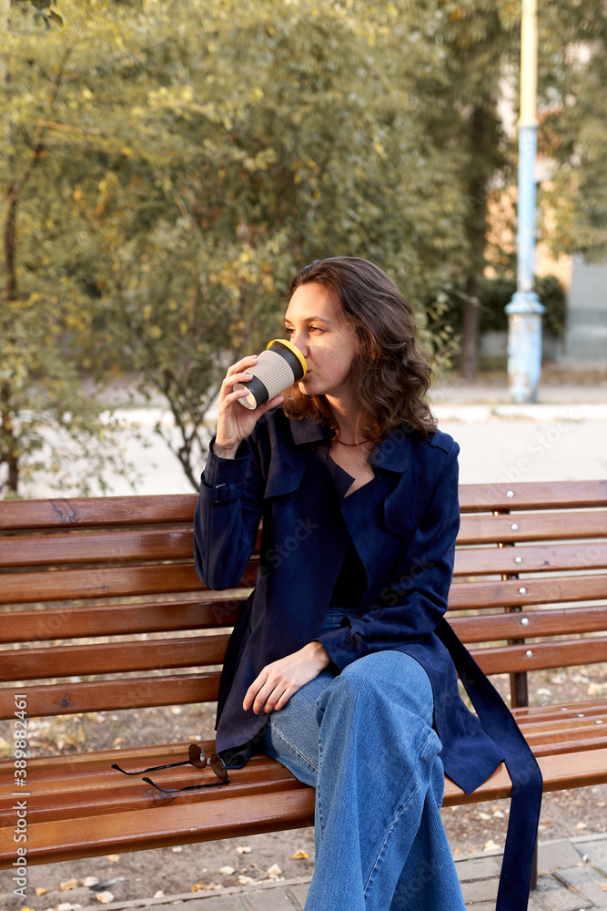 Beautiful woman with dark hair drinking coffee outdoors Beautiful woman with dark hair drinking coffee outdoors