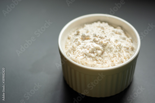 Bowl of flour on dark backdrop.Flour in ceramic cup.Starch cup with copy space