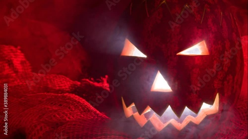 Halloween pumpkin made with watermelon in Brazil in a setting with red light and smoke, movement from right to left and zoom out.