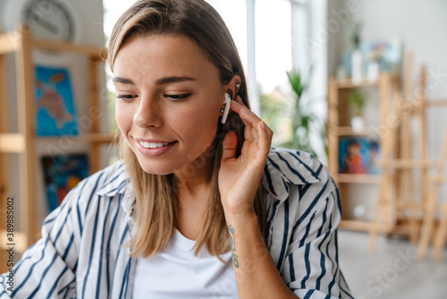 Smiling young woman talking via wireless earphones