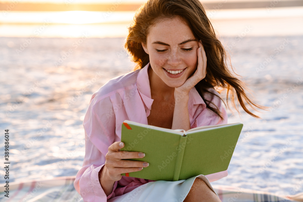 Smiling beautiful young woman reading a book