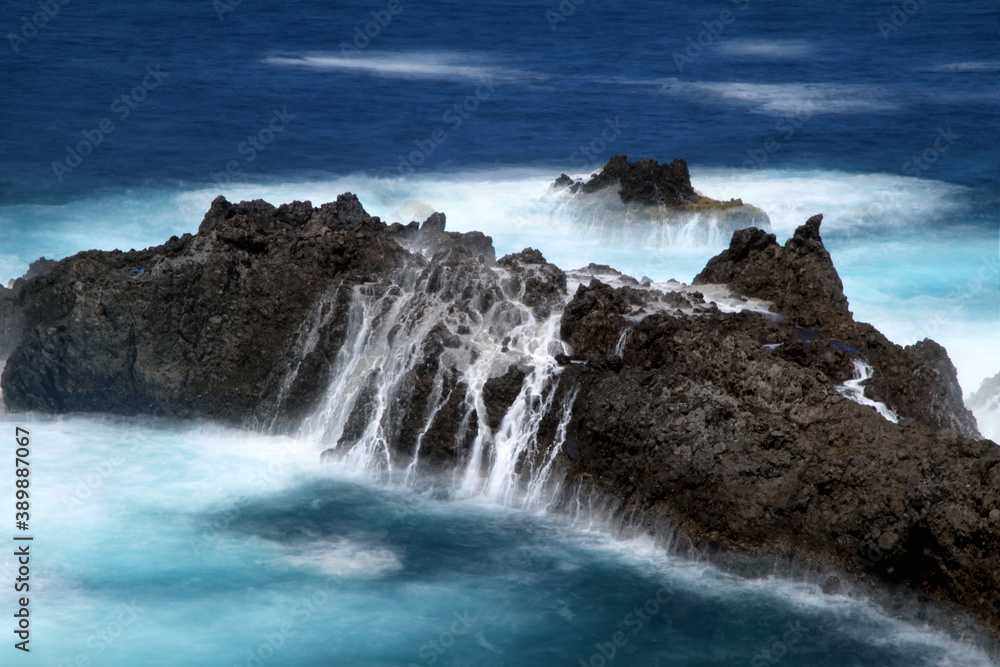 Detail of rocks with waterfalls of ocean water.