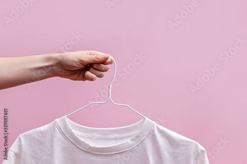 Cropped image of female hand holding hanger with white t-shirt