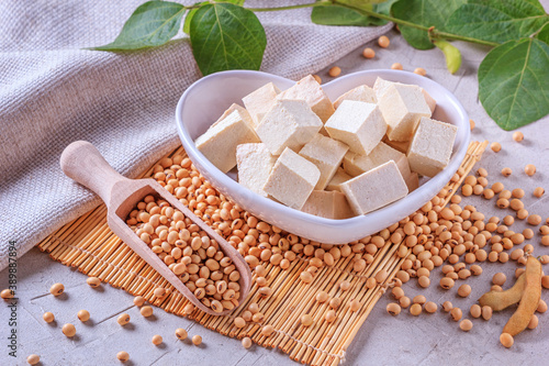 Tofu, also known as bean curd, diced in a faience white bowl in the form of heart on a bamboo napkin, closeup with selective focus