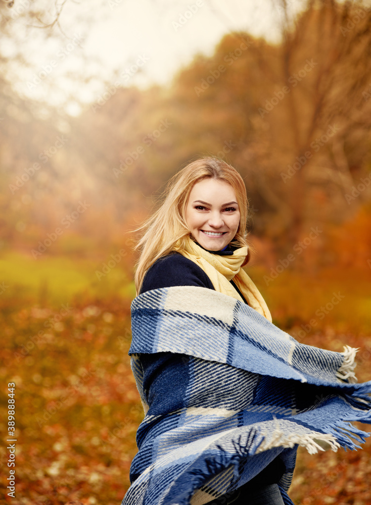 Cheerful smiling young blonde wrapped in blanket in autumn forest, getting rid of the autumn desires Cheerful smiling young blonde wrapped in blanket in autumn forest, getting rid of the autumn desires