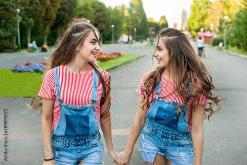 girls twins run on the background of attractions, emotions of happiness and joy, youth