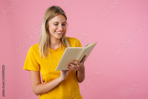 Cheerful beautiful girl smiling while reading book