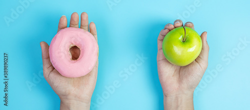 woman holding green apple and pink donut, female choose between fruit is Healthy food and sweet is unhealthy junk foods. Dieting, obesity, eating lifestyle and nutrition concept