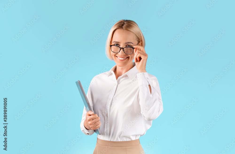 Portrait of happy female CEO holding tablet computer and smiling over blue studio background