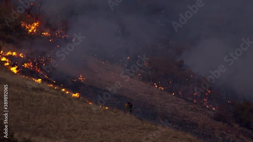 Firefighter putting out fire burning on mountainside working the hotspots as wildfire burns on mountain in Utah. photo