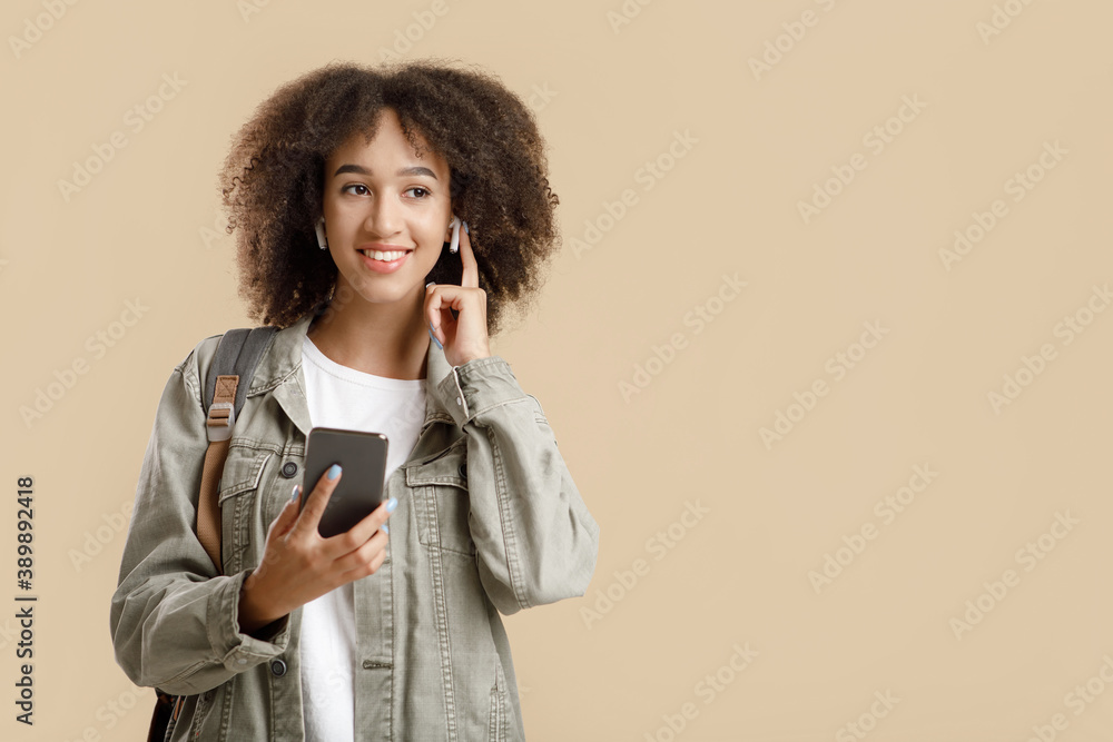Favorite music for a modern walk. Happy young stylish african american woman holds smartphone Favorite music for a modern walk. Happy young stylish african american woman holds smartphone