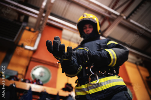 Photo Closeup of fireman putting on gloves and preparing for action while standing in fire station