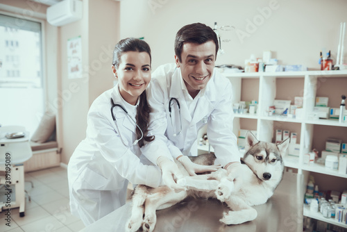 Two veterinarians in white coats look at camera.