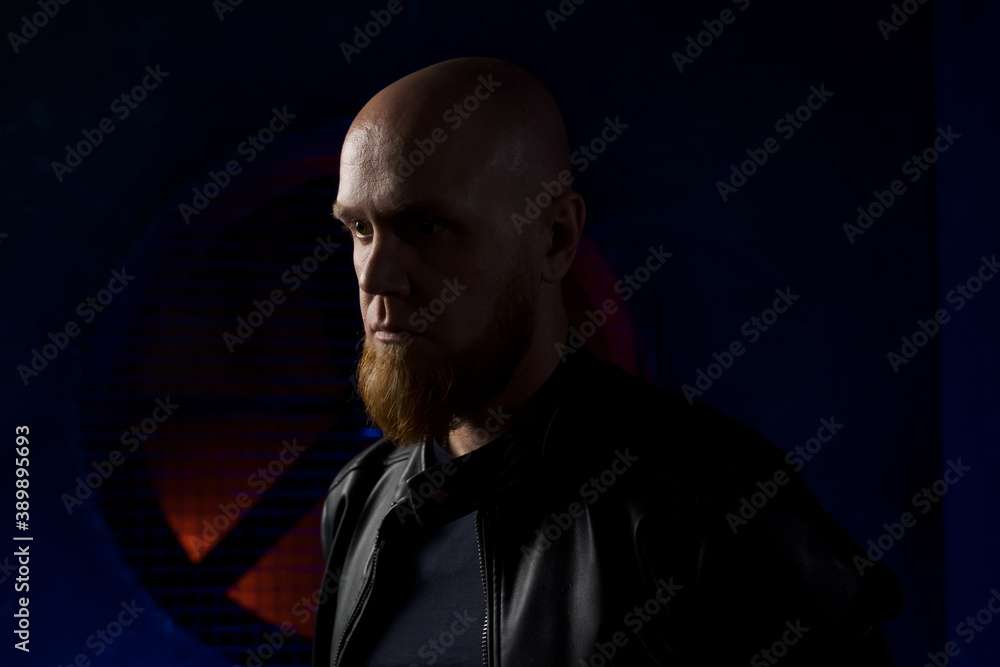 A handsome, Caucasian, stylish, bald man with a red beard looks down at his feet with a serious look. Portrait of a serious man. Close-up of the face.